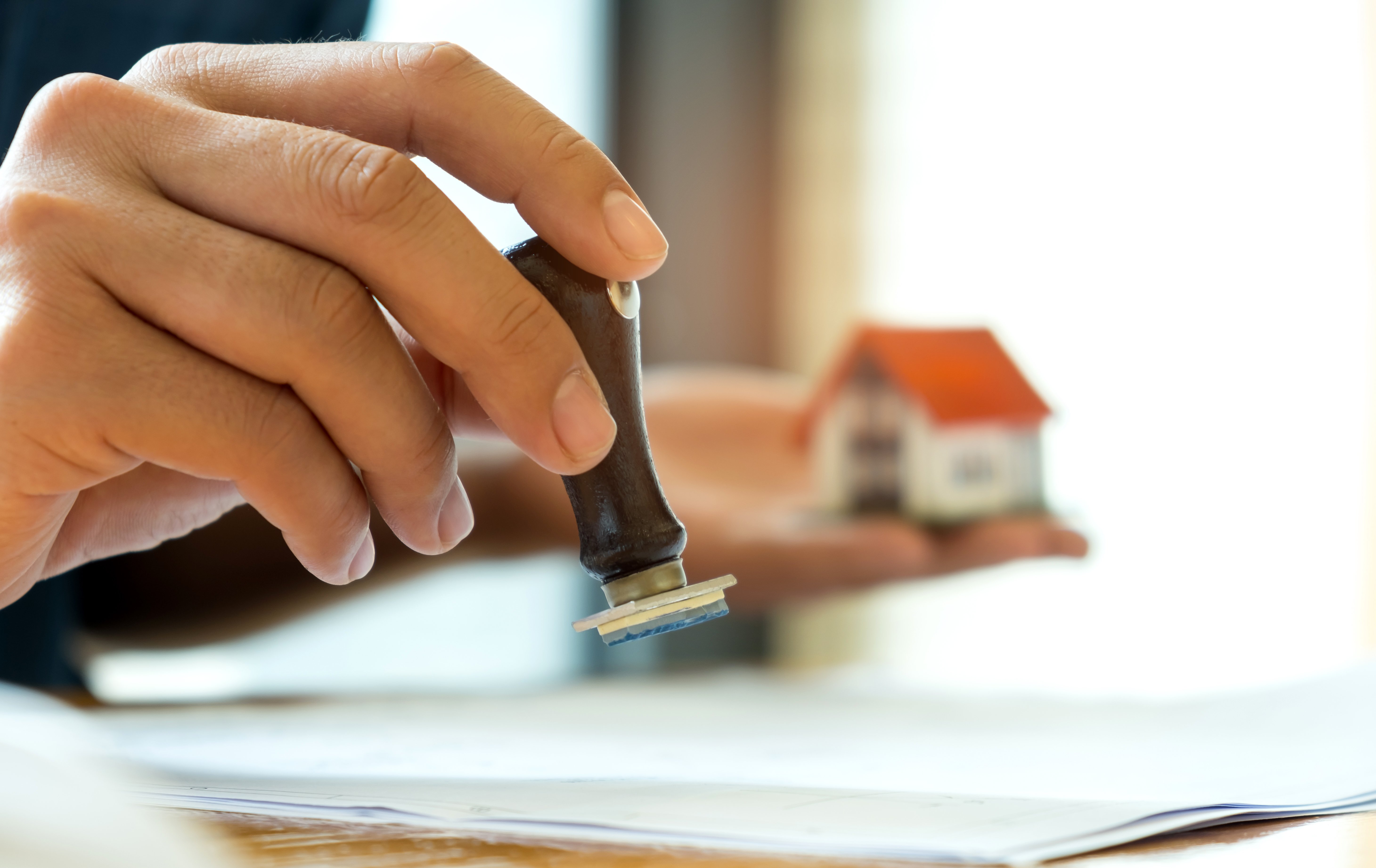 close-up-rubber-stamp-and-model-house-in-hand-P7PRWV3